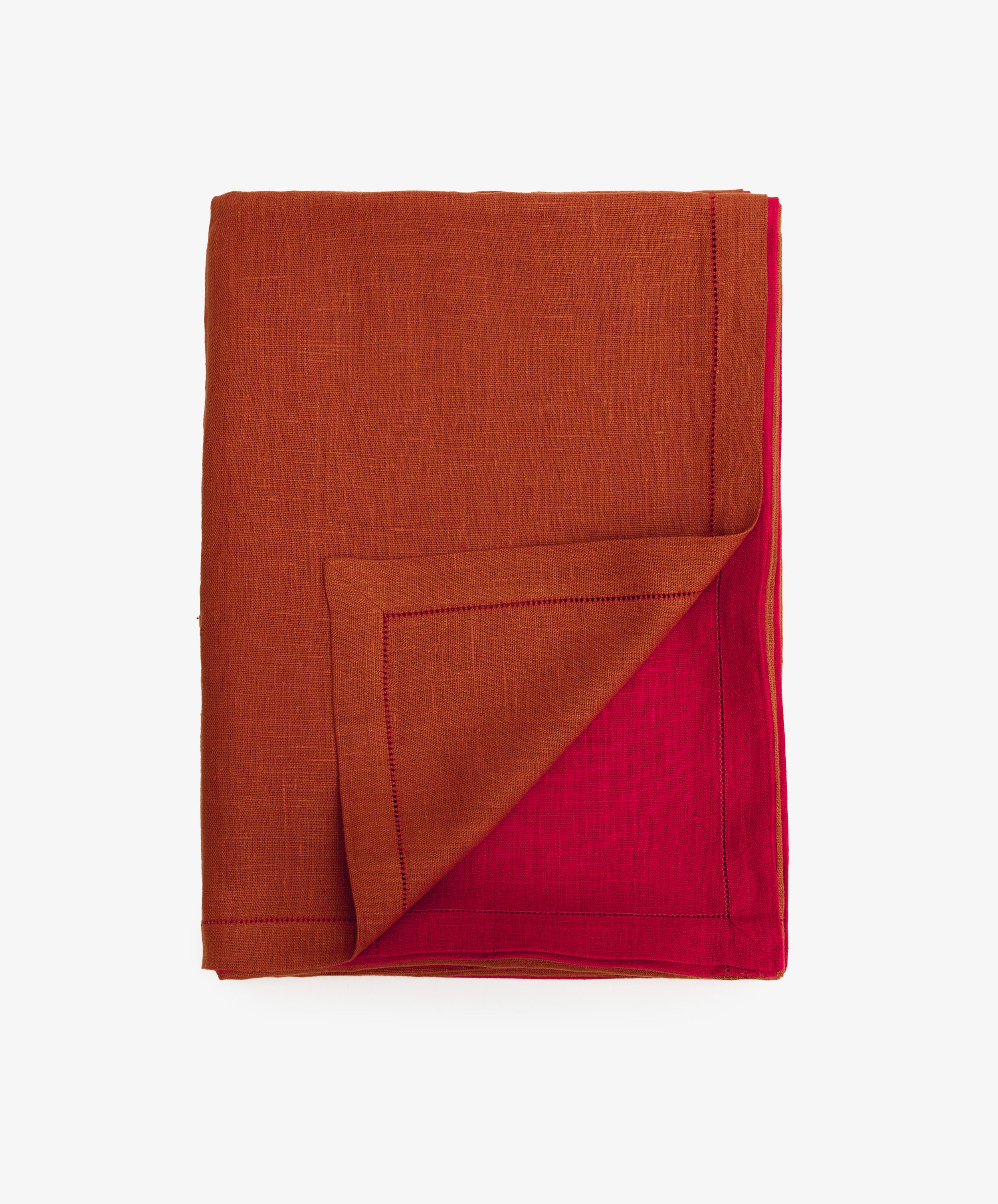 Magnetic Color Field Tablecloth. Folded terracotta linen cloth with red stitching, with bottom corner flipped up to show red side.