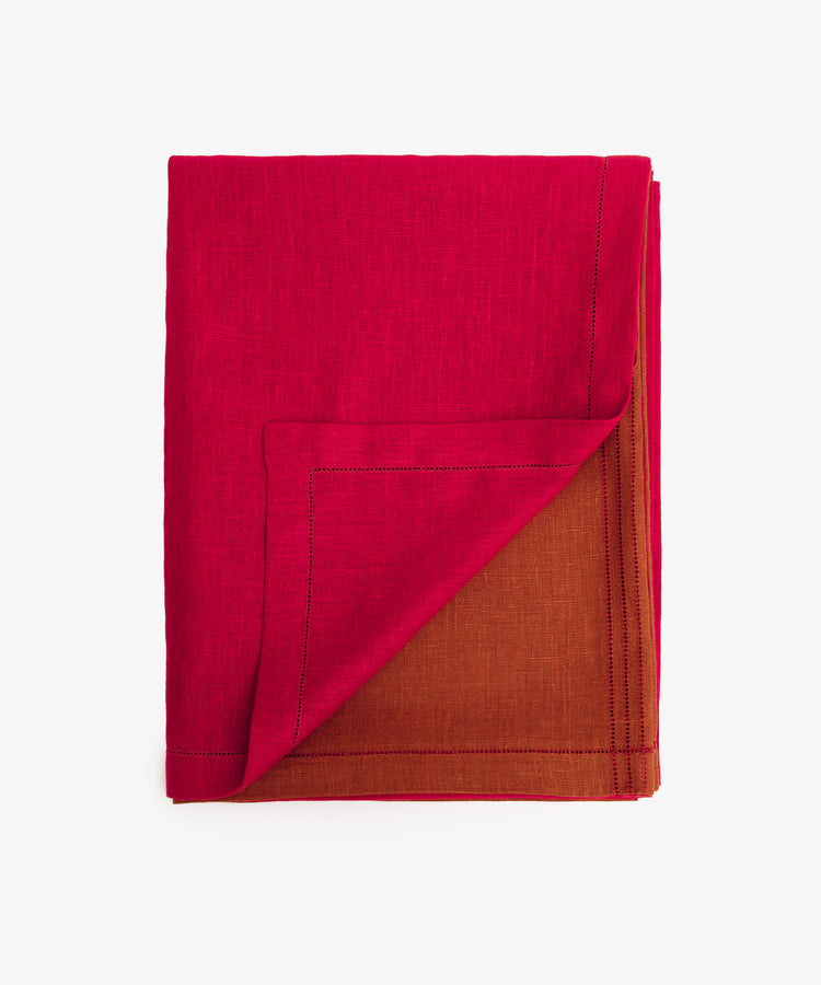 Magnetic Color Field Tablecloth. Folded red linen cloth with stitching, with bottom corner flipped up to show terracotta side.