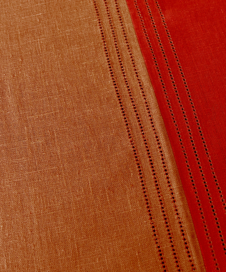 Close-up of Magnetic Color Field Tablecloth, in terracotta and red linen with stitching.