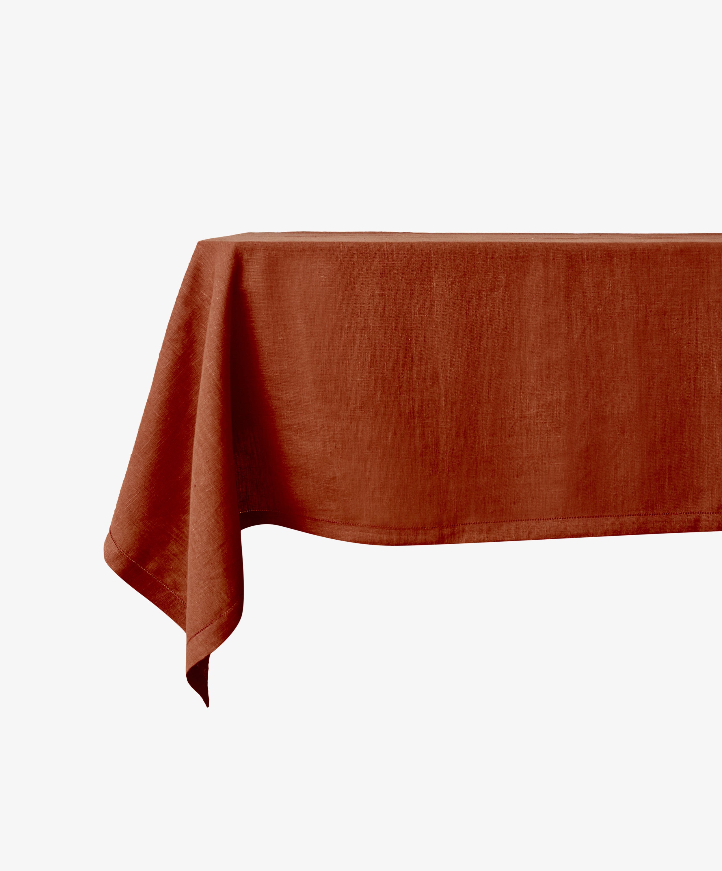 The Magnetic Colorfield Tablecloth, in a rich rust hue and crafted sustainably, covers a rectangular table set against a plain white background.