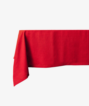 A rectangular Magnetic Colorfield Tablecloth in red linen drapes over a table against a plain white background, highlighting its sustainable craftsmanship.