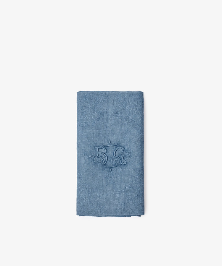 The Vintage Embroidered Napkin, Set of 6, features blue cloth napkins made from European flax with a central embroidered monogram, shown folded on a plain white background.