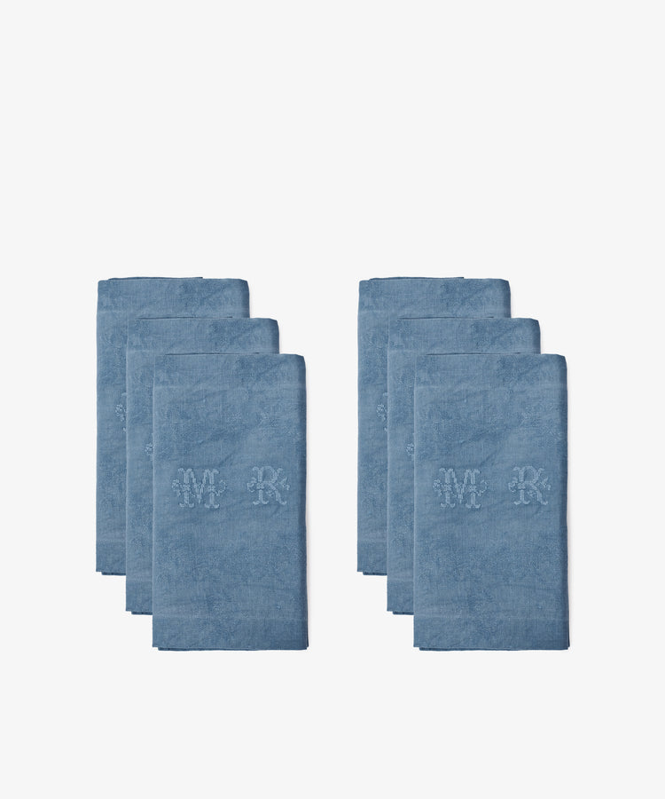 A set of six Vintage Embroidered Napkins is displayed in two groups on a plain white background, each napkin neatly folded with blue fabric and MR initials, evoking the look of classic French linens.