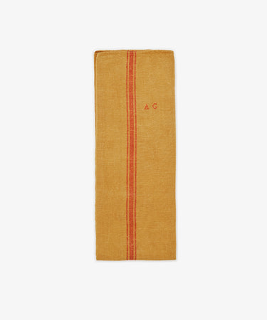 The French Vintage Tea Towel is a rectangular mustard yellow linen design inspired by Provence, featuring a vertical red center stripe and embroidered red letters 