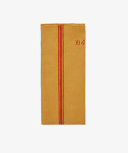 The French Vintage Tea Towel features mustard yellow linen with a central red stripe and “MG” embroidered in red in the top right, inspired by classic Provence designs—a charming accent for any kitchen.