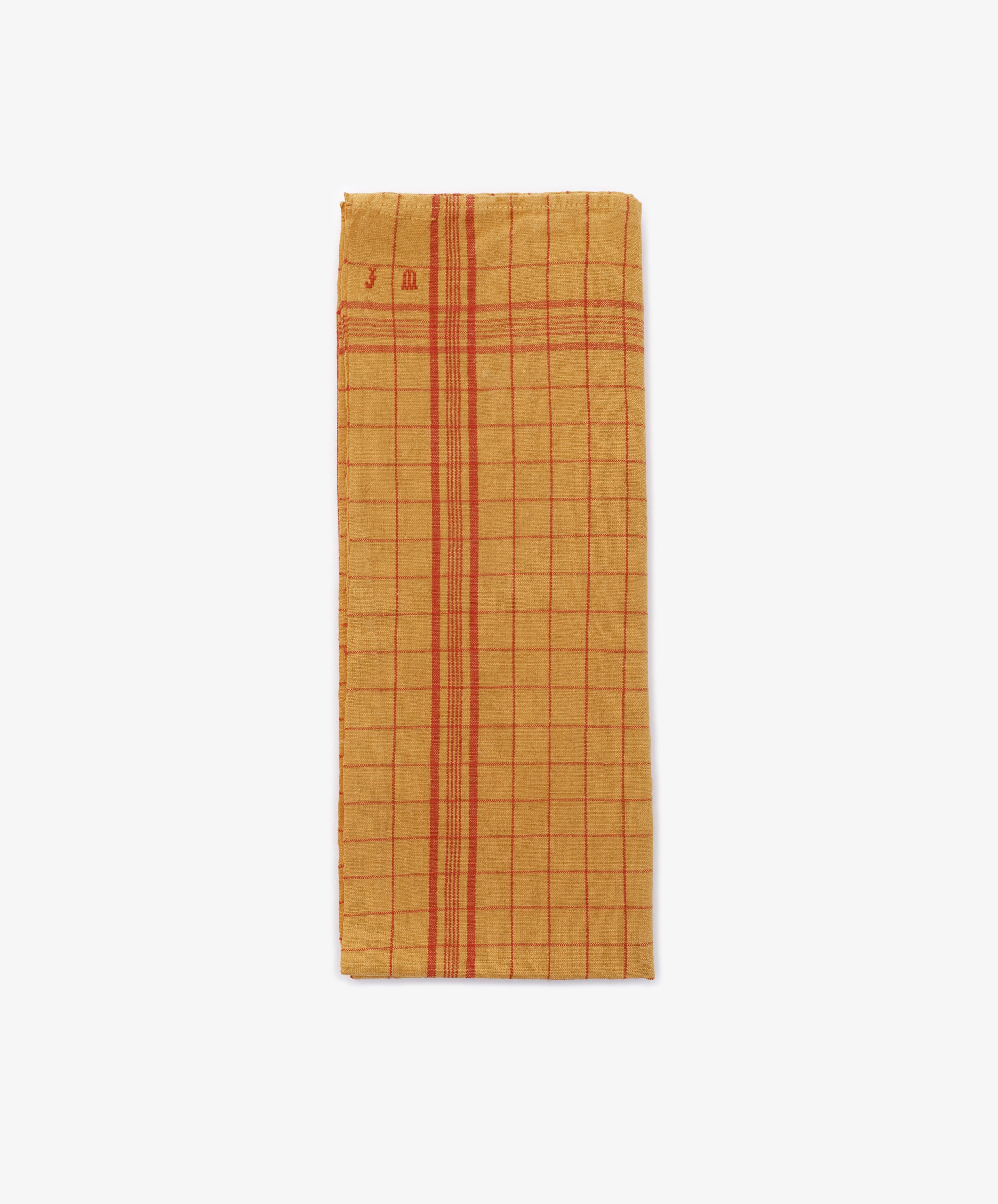 A French Vintage Tea Towel, rectangular and yellow with red grid and stripe patterns, is displayed against a white kitchen background, evoking classic Provençal style.