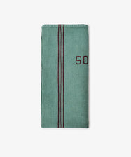 The French Vintage Tea Towel is a folded green cloth napkin with a vertical black and red stripe and partial red embroidered text on the right side, inspired by classic Provence linen, displayed on a plain white background.