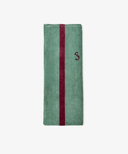 The French Vintage Tea Towel features folded green fabric with a vertical maroon stripe and a small maroon S embroidered on the right side, capturing the nostalgic charm of classic Provencal linens.
