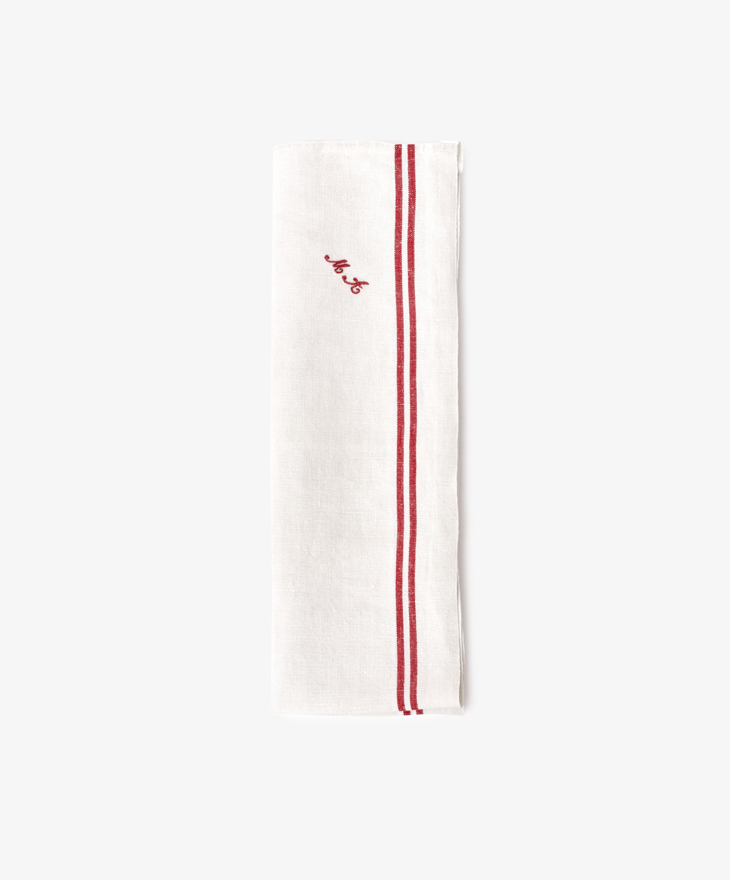 The French Vintage Tea Towel is a white linen napkin folded lengthwise with two parallel red stripes and a small red embroidered script near the top, evoking classic vintage tea towel style.