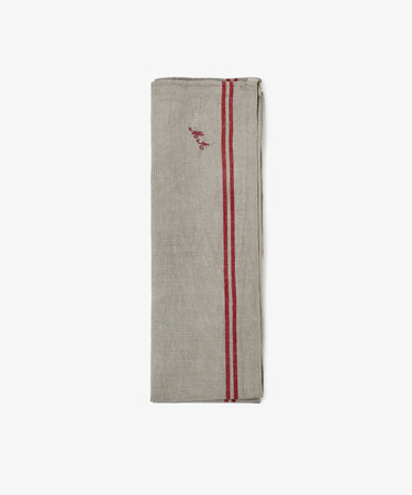 A French Vintage Tea Towel in beige linen, folded, featuring two red stripes and small embroidered red initialsâ€”evoking Provence charm and classic vintage tea towelsâ€”displayed on a plain white background.