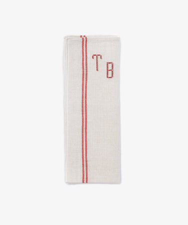 The French Vintage Tea Towel is a folded beige napkin with red embroidered initials 