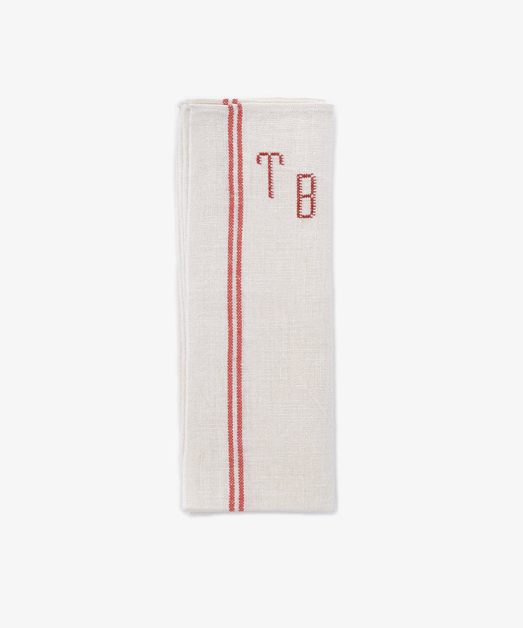 The French Vintage Tea Towel is a folded beige napkin with red embroidered initials 