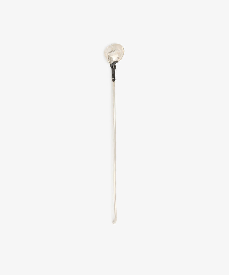 The Oyster Shell Cocktail Stirrer is a long, thin sterling silver stick with a rounded, irregular top, handcrafted and photographed on a plain white background.