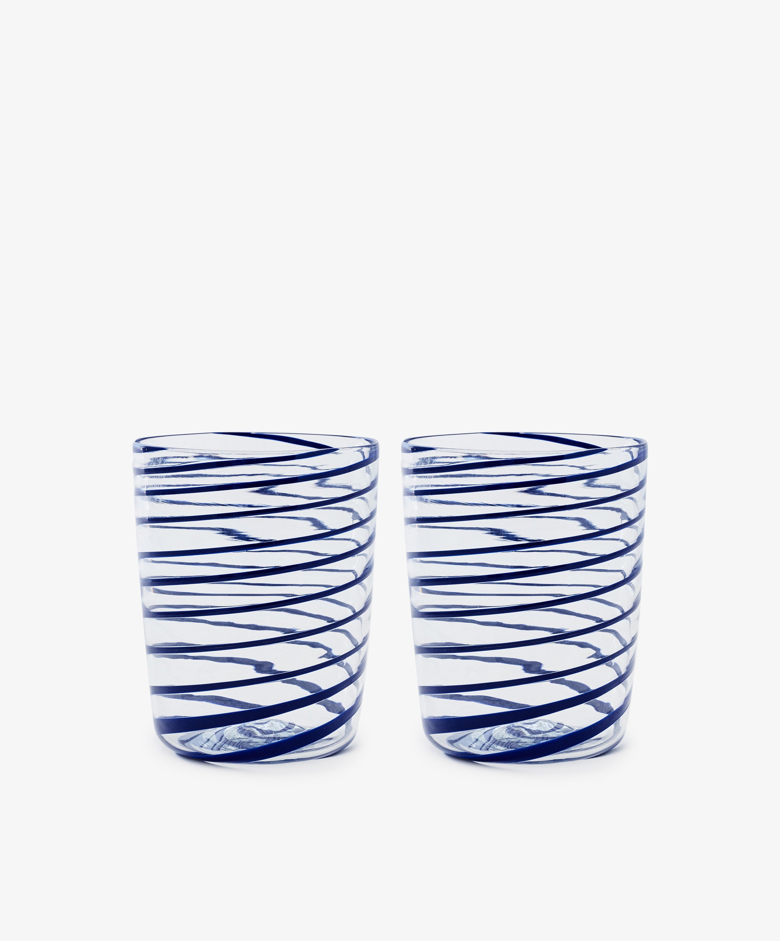 The Spirale Glass, Set of 2, features clear Murano glasses with blue spirals, displayed side by side on a white background to highlight the refined beauty of Italian craftsmanship.
