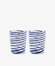 The Spirale Glass, Set of 2, features clear Murano glasses with blue spirals, displayed side by side on a white background to highlight the refined beauty of Italian craftsmanship.