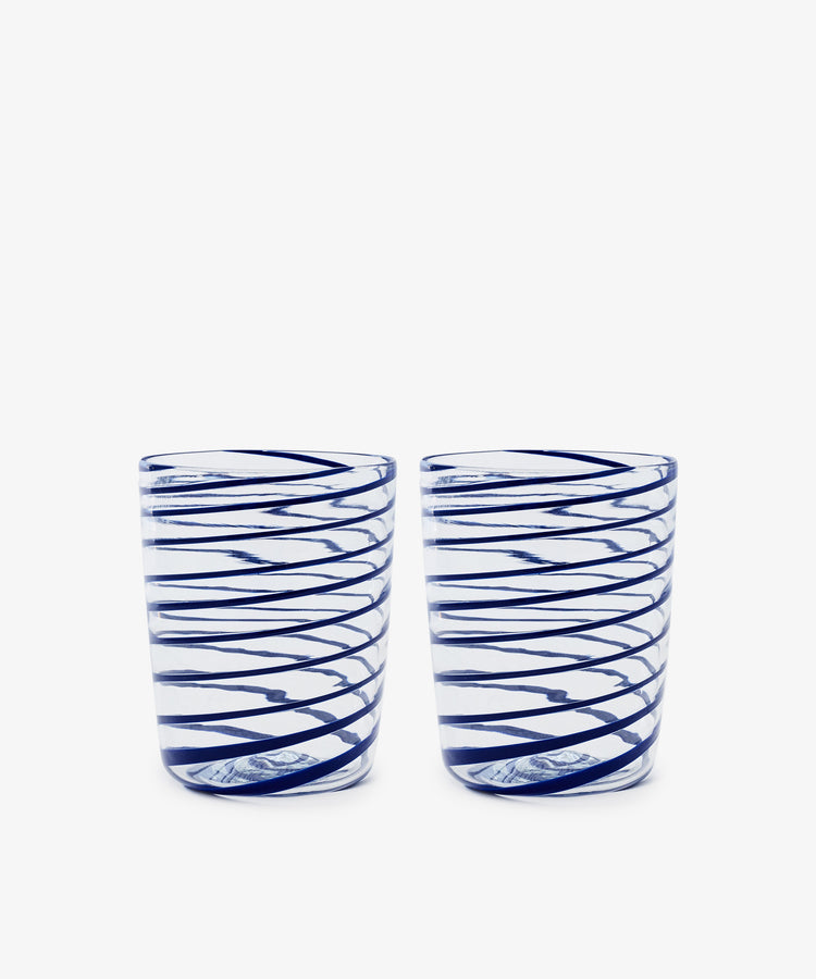 The Spirale Glass, Set of 2, features clear Murano glasses with blue spirals, displayed side by side on a white background to highlight the refined beauty of Italian craftsmanship.