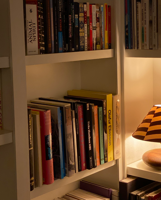 Bookshelf with a lit striped table lamp