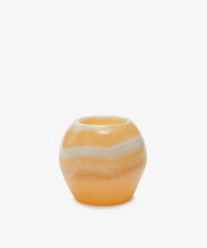 The Akila Candleholder features round, orange and white striped Egyptian alabaster with a small central opening, displayed against a plain white background.