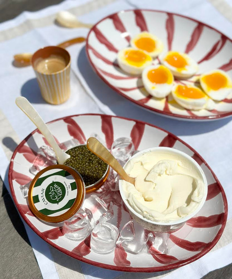 Bowls of caviar and cream on ice with halved soft-boiled eggs in the background