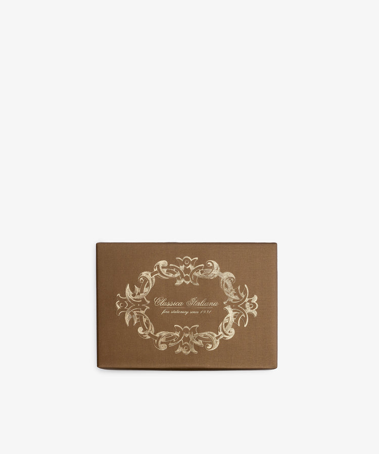 Rectangular brown box with an ornate, cream-colored decorative border and the text “Classica Italiana fine stationery since 1901” on the lid, set against a plain white background. Contains the Bordered Correspondence Card & Envelope, Set of 25—perfect for holding wedding thank-you cards or elegant cream envelopes crafted from luxurious cotton paper.