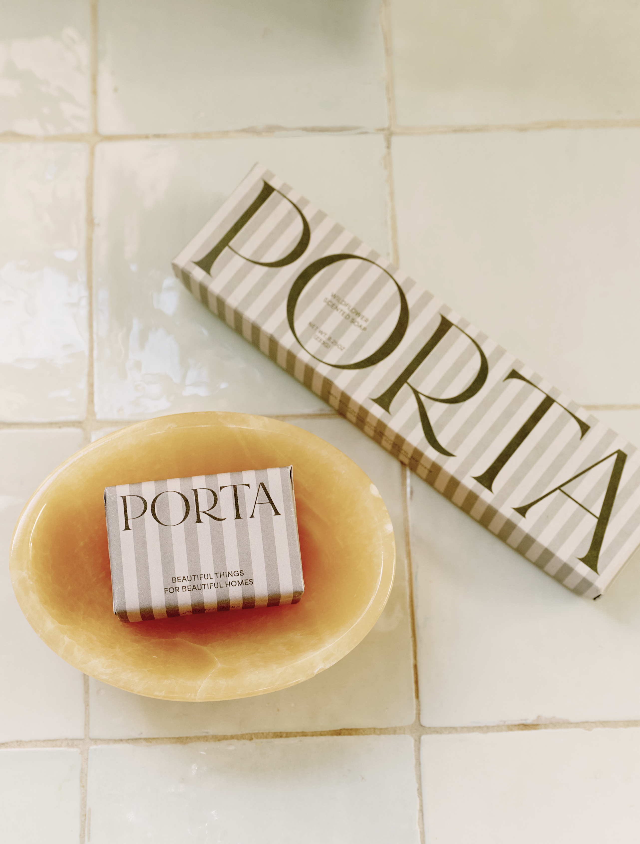 The Squeaky Clean Bundle, featuring a boxed bar of soap in a yellow Akila catchall dish beside its striped packaging on tiled surfaces, makes a thoughtful gift for everyday rituals.