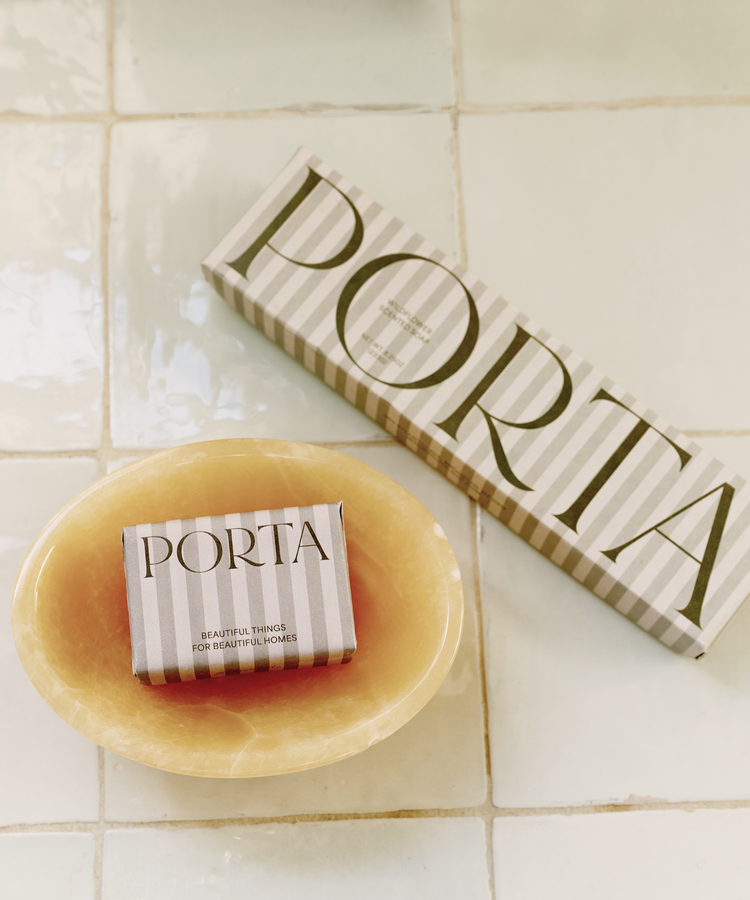 The Squeaky Clean Bundle, featuring a boxed bar of soap in a yellow Akila catchall dish beside its striped packaging on tiled surfaces, makes a thoughtful gift for everyday rituals.