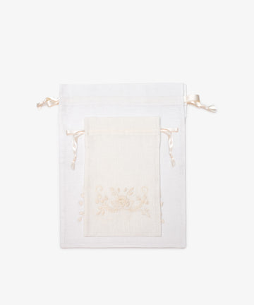 Two handmade white Linen Drawstring Bags from Portugal, in large and small sizes, feature subtle Viana do Castelo embroidery and ribbon ties. Both are displayed against a plain white background.