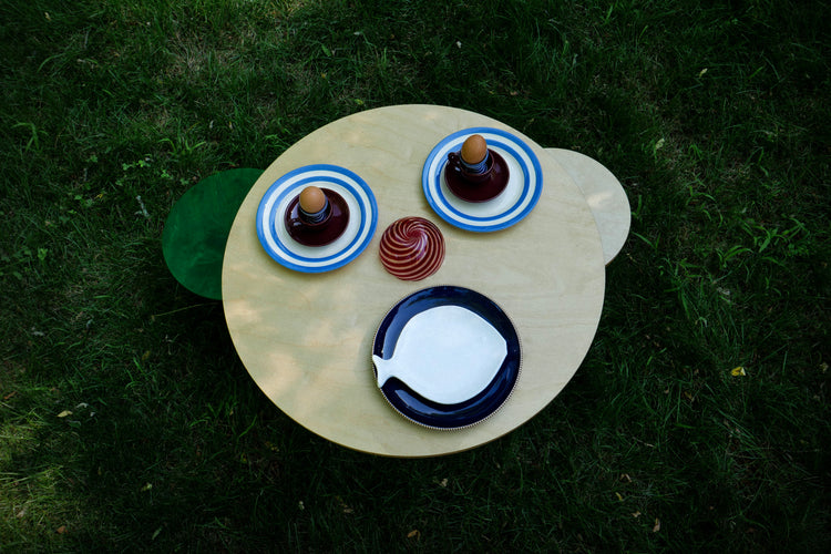 Striped fish-shaped plate with a blue cup holding an eggs, next to a blue cup and saucer