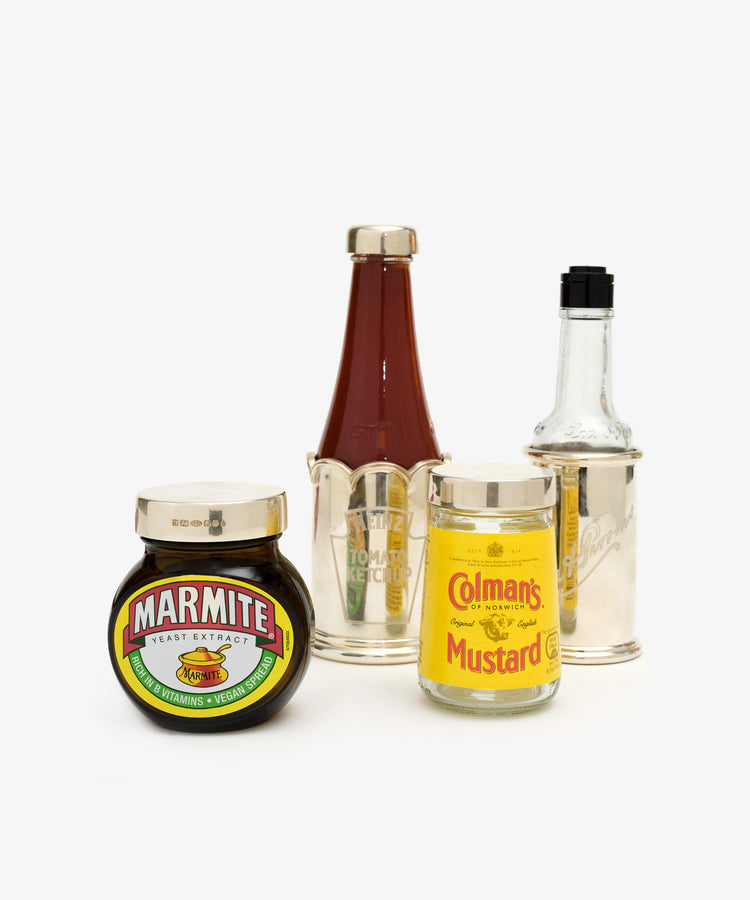 Grouping of condiment bottles and jars with silver lids and sleeves.