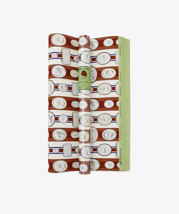 A rolled sheet of Intaglio Stripe Gift Wrap in red and green with a repeating white coin pattern and a vintage-style Parvum Opus label on the front.