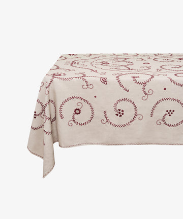 Tan cotton Inez Tablecloth with red embroidery spread and draped over invisible table.