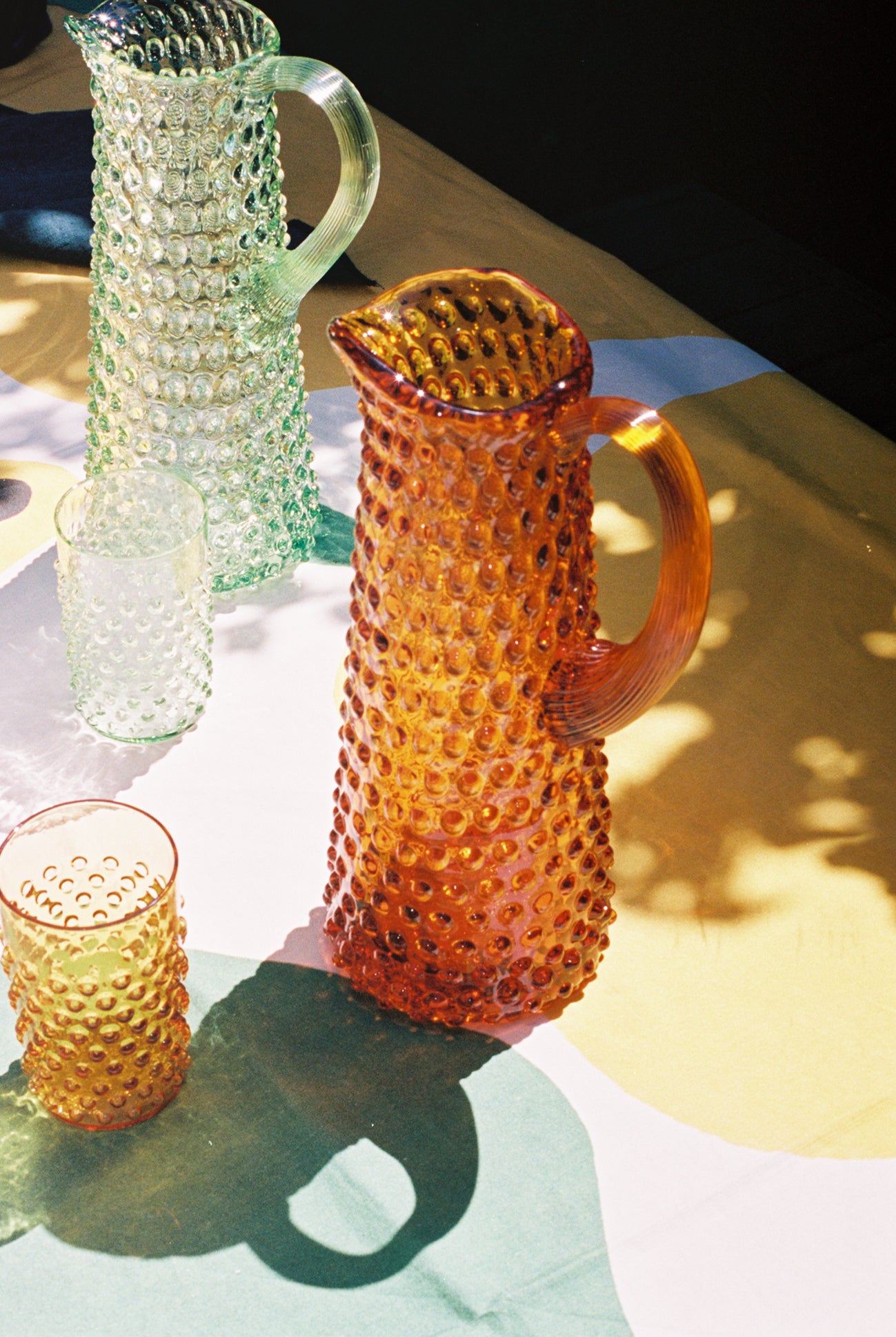 Main Squeeze Tablecloth in situ with colored glass hobnail pitchers and glass.