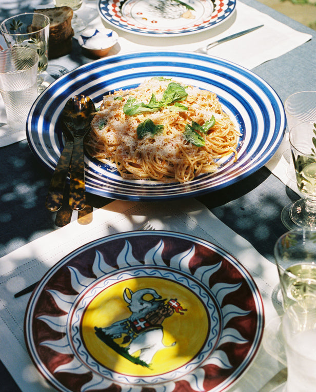 Palio dinner plates in situ on outdoor table with spaghetti and wine.