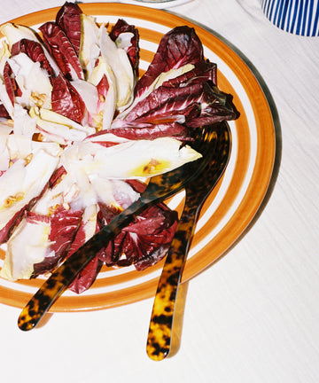 Natalia Platter on tablecloth, holding radicchio salad and tortoise utensils.