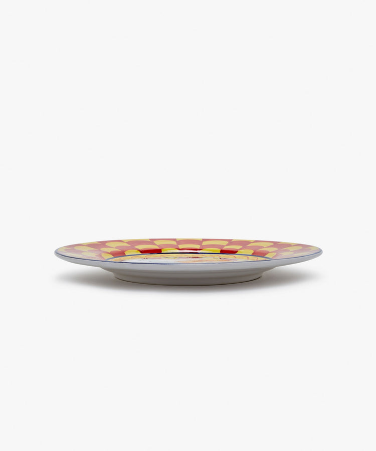 Palio Dinner Plate. Glazed ceramic in red and yellow designs with snail motif, angled side view.