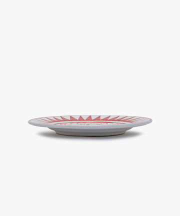 Palio Dinner Plate. Glazed ceramic in red and white designs with giraffe motif, angled side view.