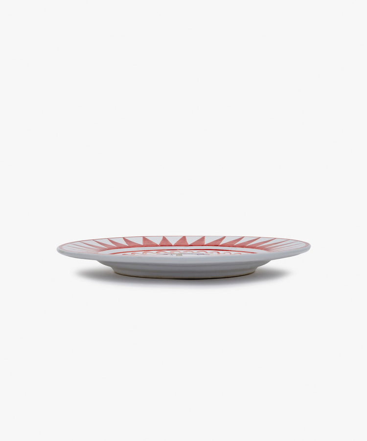Palio Dinner Plate. Glazed ceramic in red and white designs with giraffe motif, angled side view.