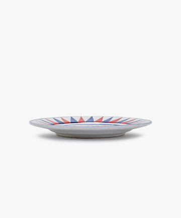 Palio Dinner Plate. Glazed ceramic in red and blue designs with panther motif, angled side view.