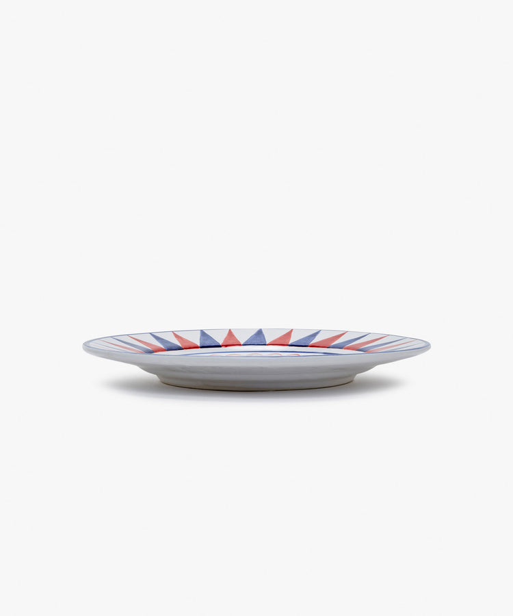 Palio Dinner Plate. Glazed ceramic in red and blue designs with panther motif, angled side view.