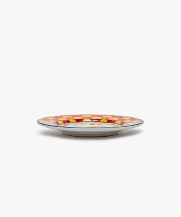 Palio Small Plate in white glazed ceramic with red and yellow designs, side view.