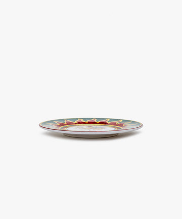 Palio Small Plate in white glazed ceramic with red and green designs, side view.