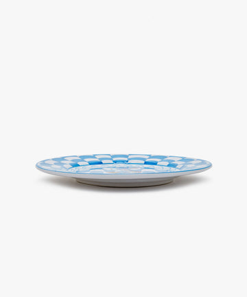 Palio Dinner Plate. Glazed ceramic in blue and white designs with fish motif, angled side view.