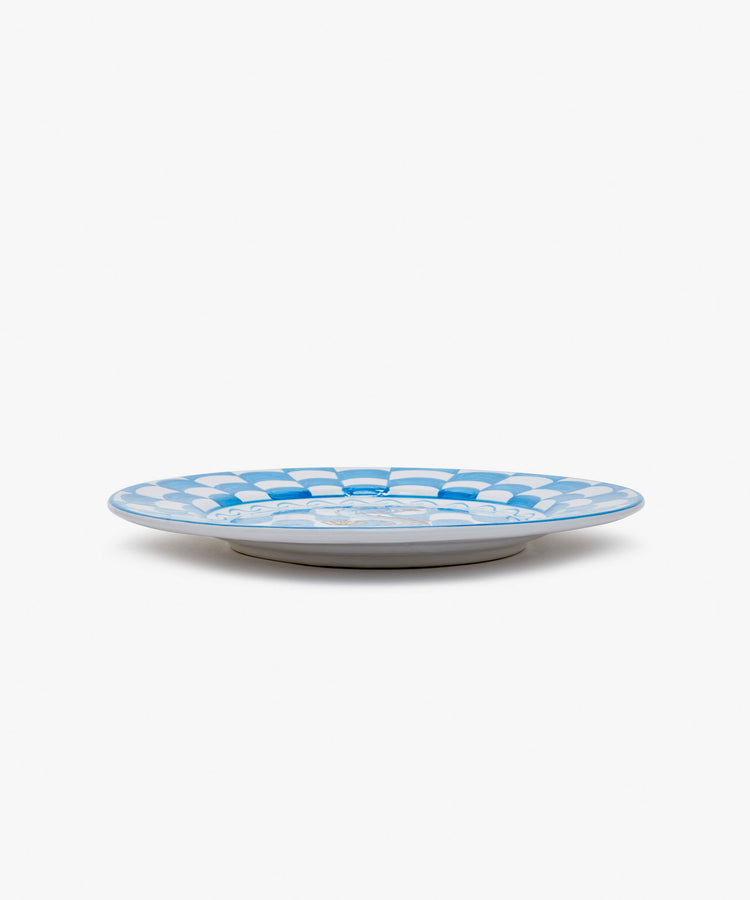Palio Dinner Plate. Glazed ceramic in blue and white designs with fish motif, angled side view.