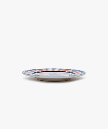 Palio Small Plate in white glazed ceramic with blue and red designs, side view.