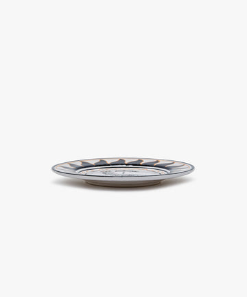 Palio Small Plate in white glazed ceramic with black and orange designs, side view.