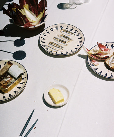 Tablescape with assorted plates and food on white tablecloth.