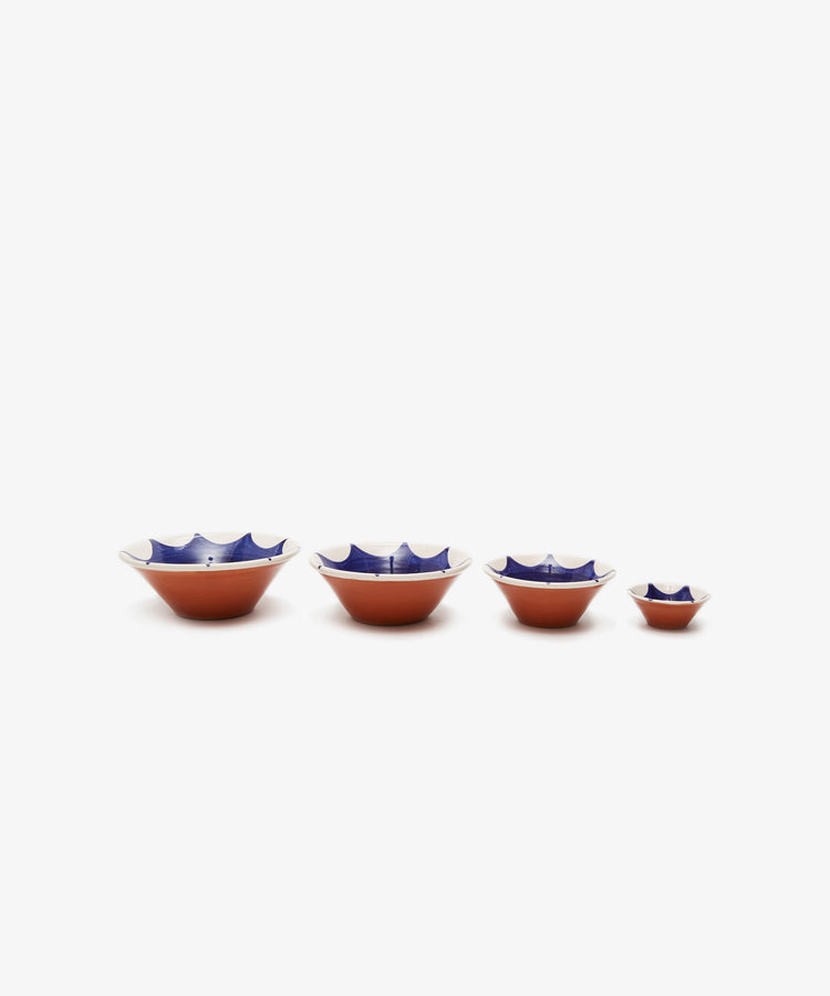 Row of 4 Stella Nesting Bowls, in glazed terracotta with white rim and interior and dark blue design.