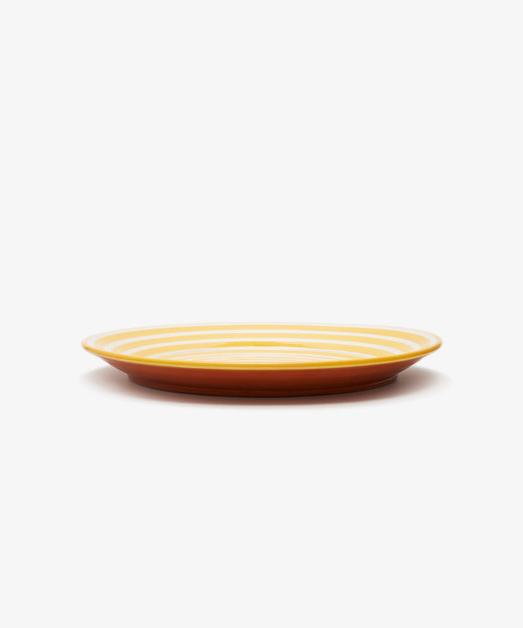 Natalia Platter. Yellow and white spiral striped glazed terracotta plate, angled side view.