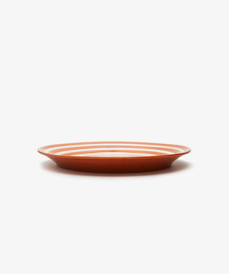 Natalia Platter. Orange and white spiral striped glazed terracotta plate, angled side view.