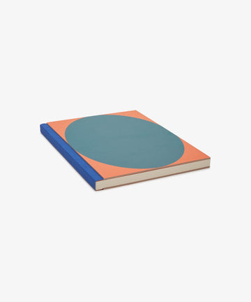 Dreamer's Notebook. Rectangular book with orange background, teal oval, and blue bound spine, angled flat view.